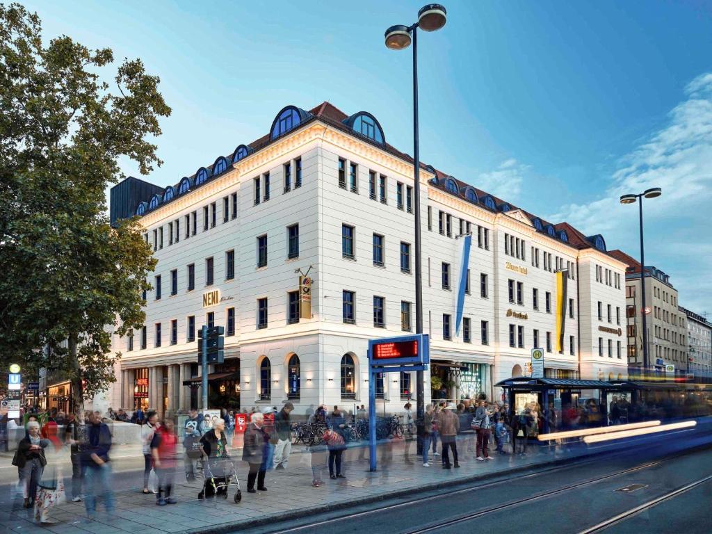 a large white building on a busy city street at 25hours Hotel The Royal Bavarian in Munich