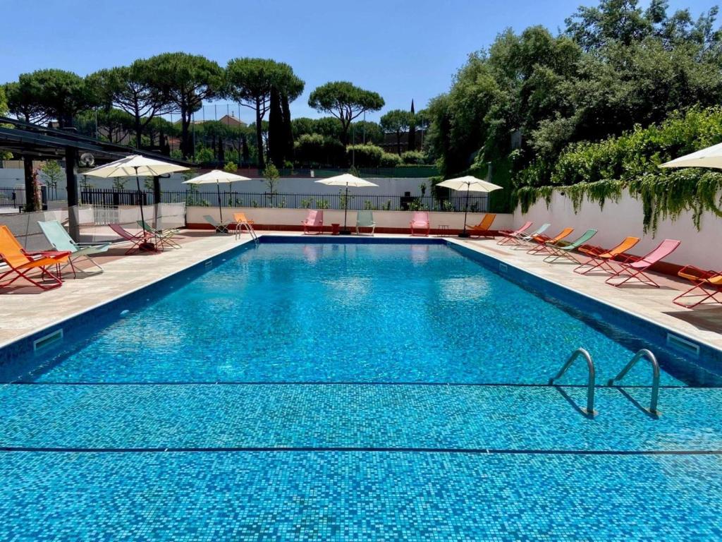 a large swimming pool with chairs and umbrellas at Ibis Styles Roma Aurelia in Rome