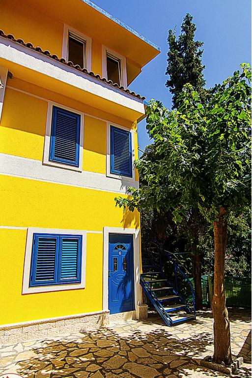 a yellow house with a blue door and a tree at Gregor Villa in Asim Zeneli