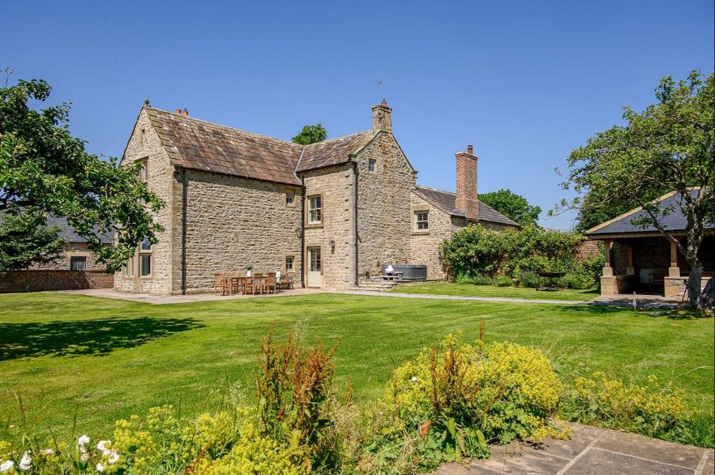 an old stone house with a grass yard at Hollins Farmhouse in Leyburn