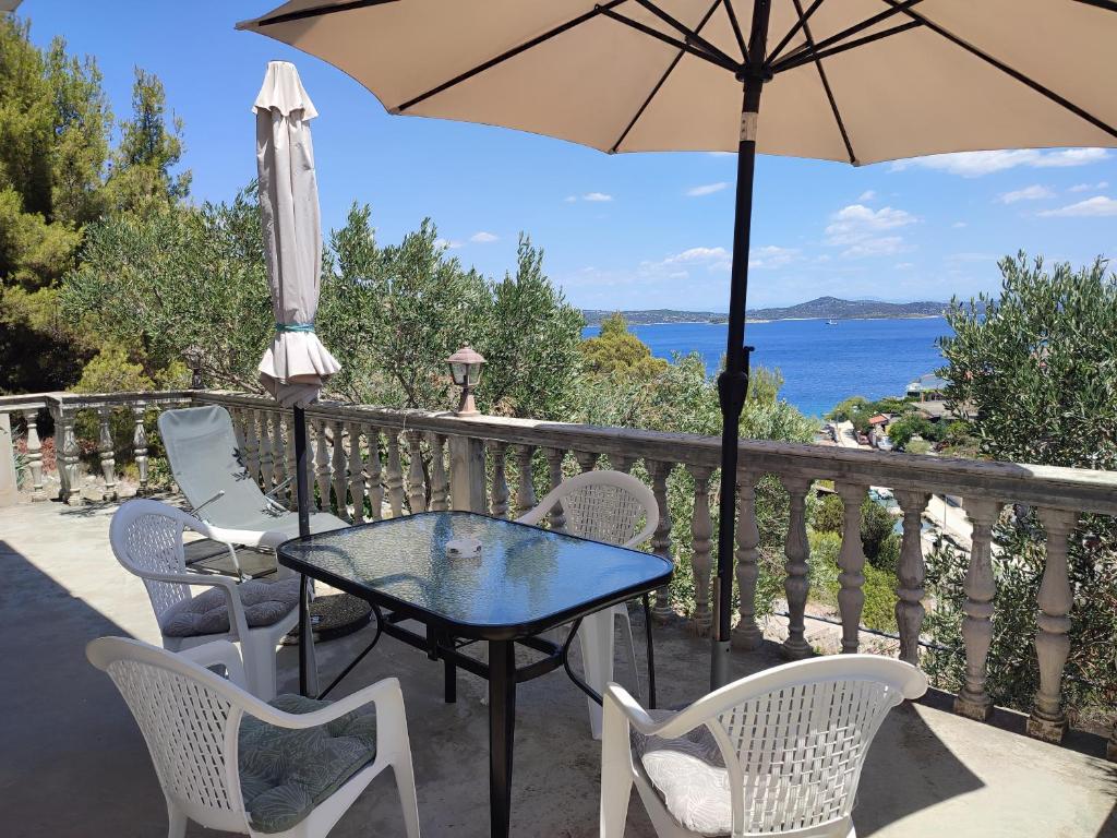 a table and chairs with an umbrella on a balcony at Apartment Skroza in Žirje