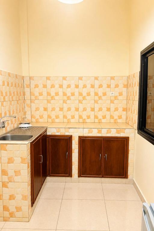 a kitchen with wooden cabinets and a counter top at Akenon Appart Hotel in Ouagadougou