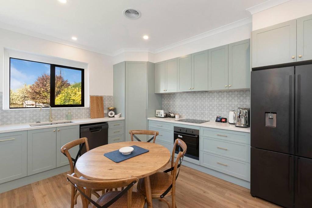 a kitchen with a wooden table and a black refrigerator at Lava House WIFI central heating cooling CBD in Warrnambool