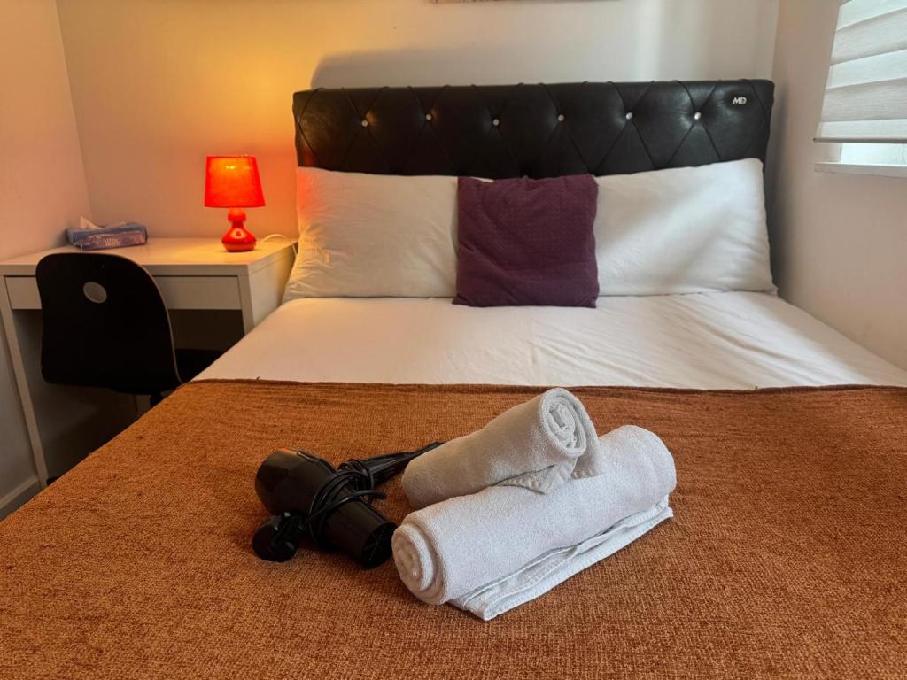 a bed with two towels and a camera on it at Cosy Private Bedrooms in Euston Station in London