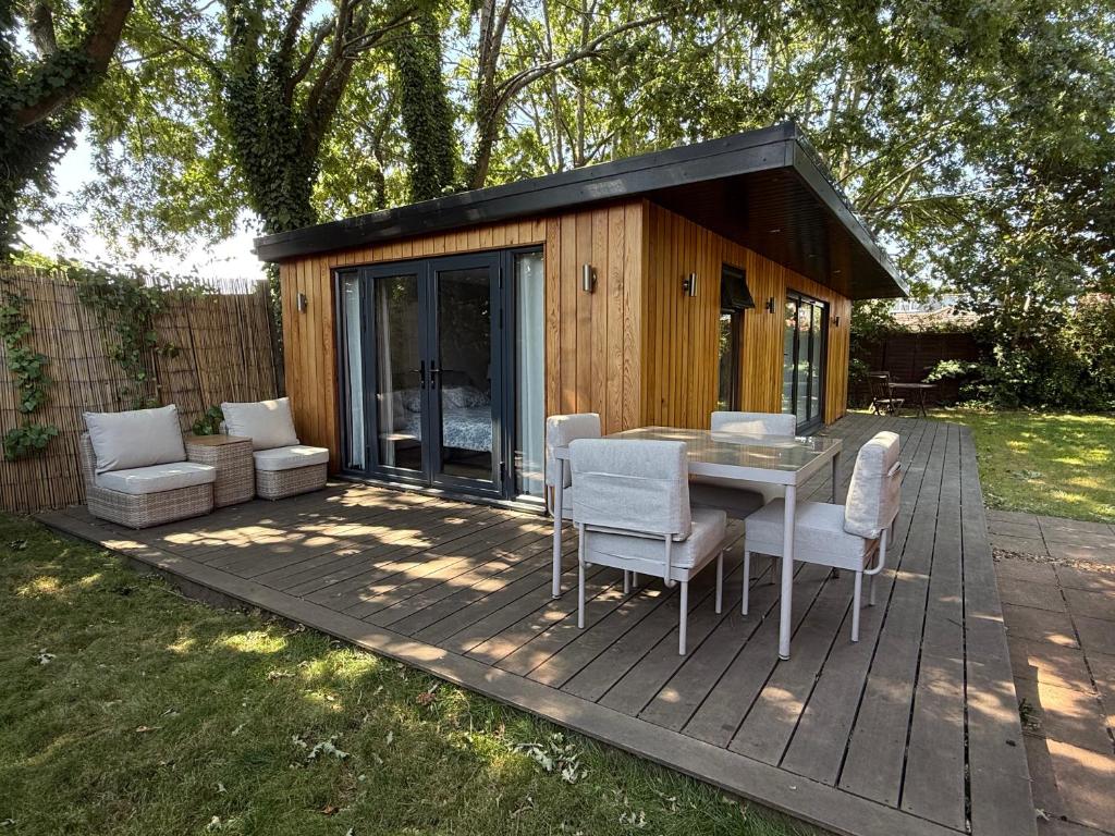 a small cabin with a table and chairs on a deck at Oak Lodge in Hambledon