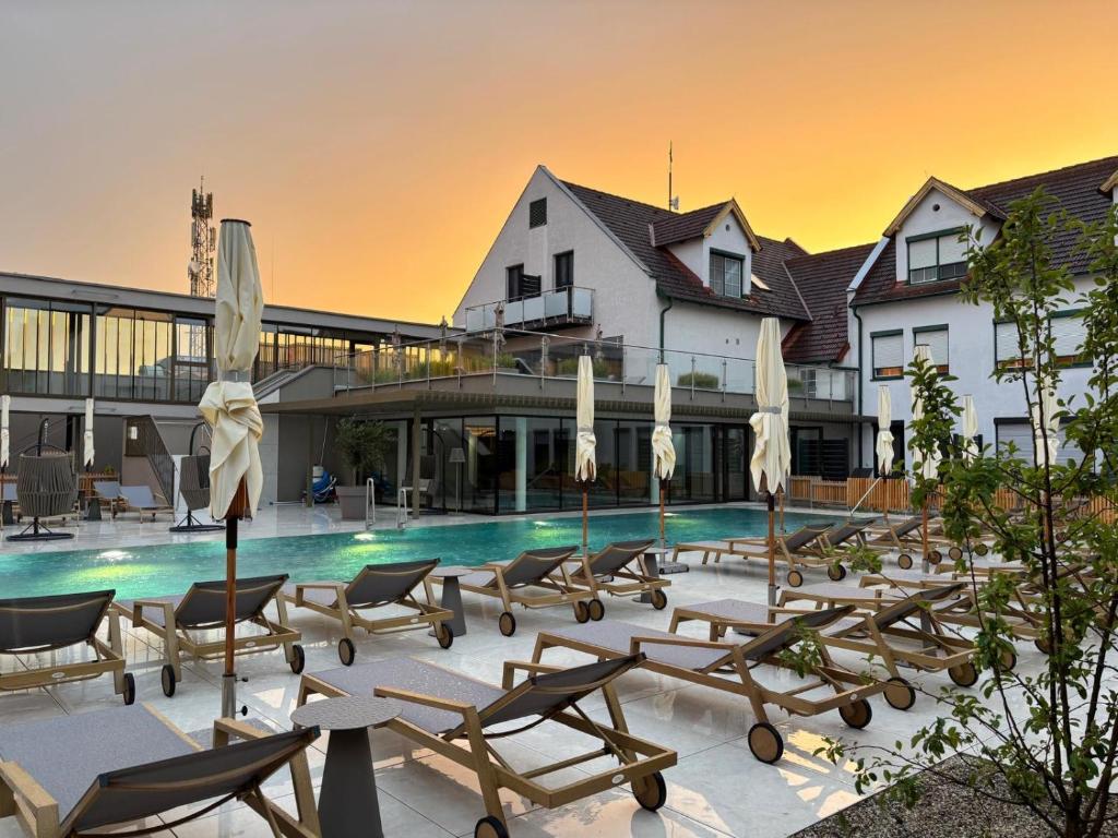 a pool with chairs and umbrellas in front of a building at Hotel Nationalpark in Illmitz