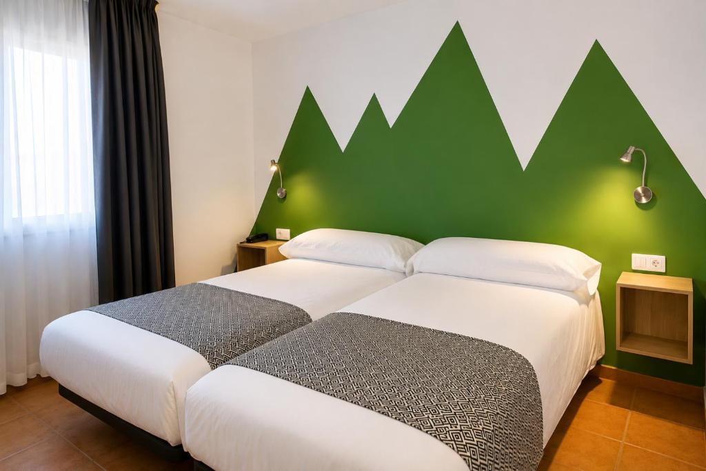 two beds in a hotel room with a green wall at Hotel Musher in Pas de la Casa