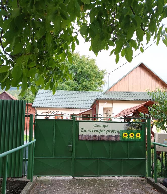 a green gate with a sign in front of a house at Chalupa Za zeleným plotom in Pača