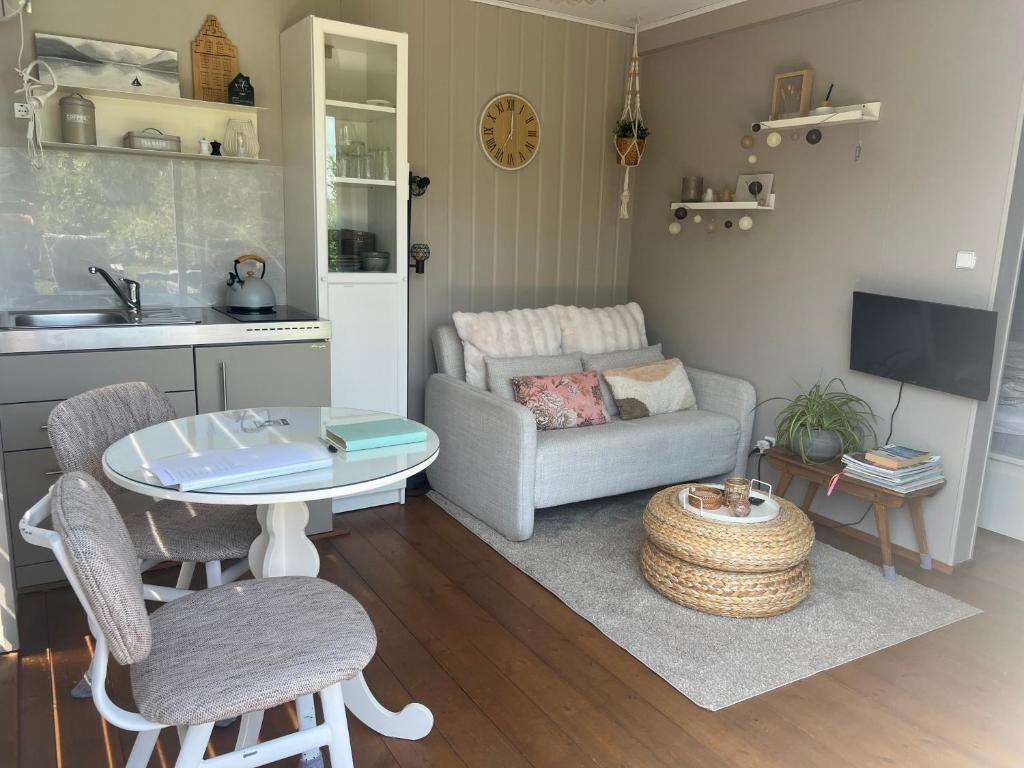 a living room with a table and a couch at Tiny House Droom aan de Linge in Wadenoijen