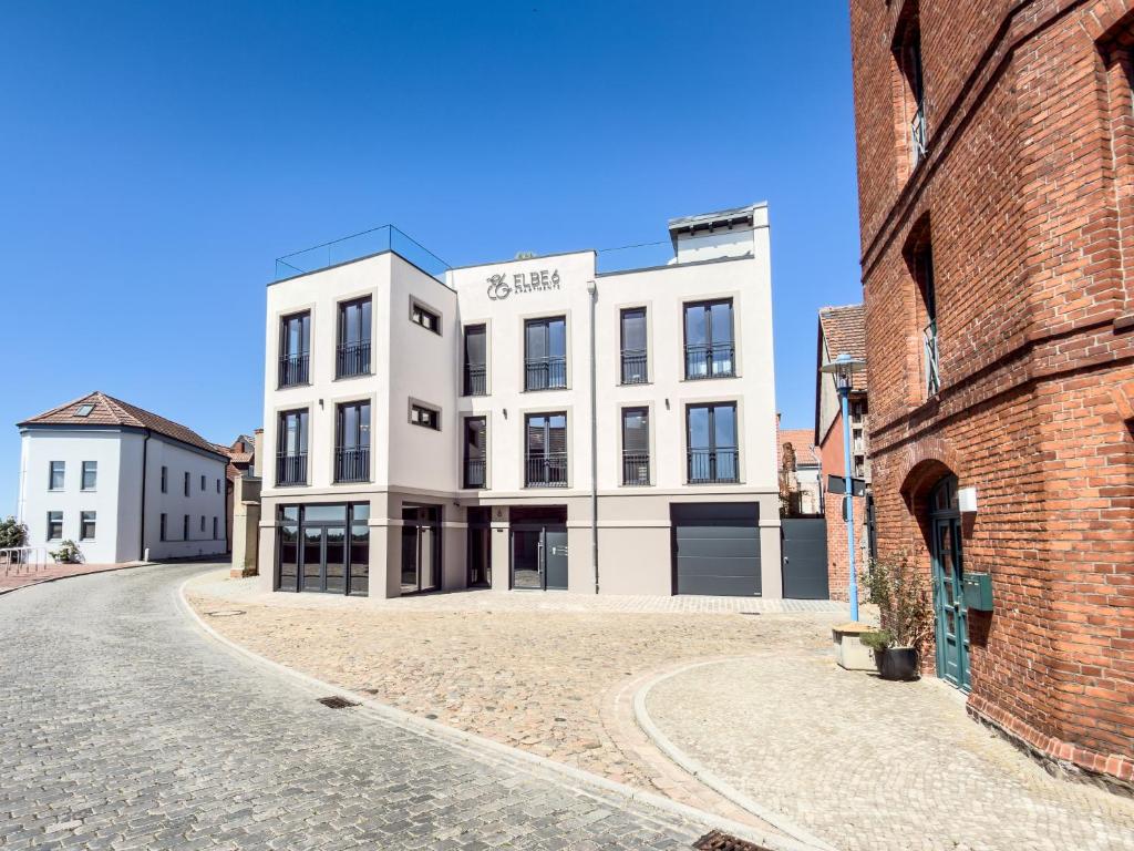 a white building on a street next to a brick building at ELBE6 Apartments in Wittenberge