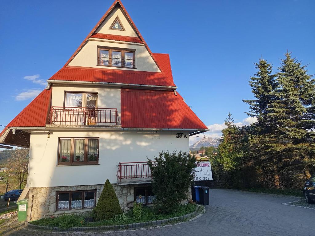 a house with a red roof and a driveway at Pokoje gościnne u Kasecki in Murzasichle