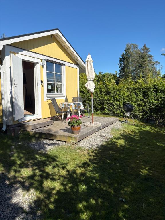 a small yellow house with a patio and an umbrella at Söt stuga in Strömstad