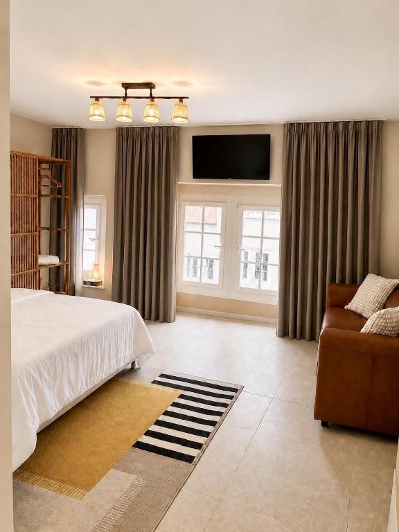 a bedroom with a bed and a couch and windows at Cosy studio dans un quartier animé et pittoresque in Fribourg