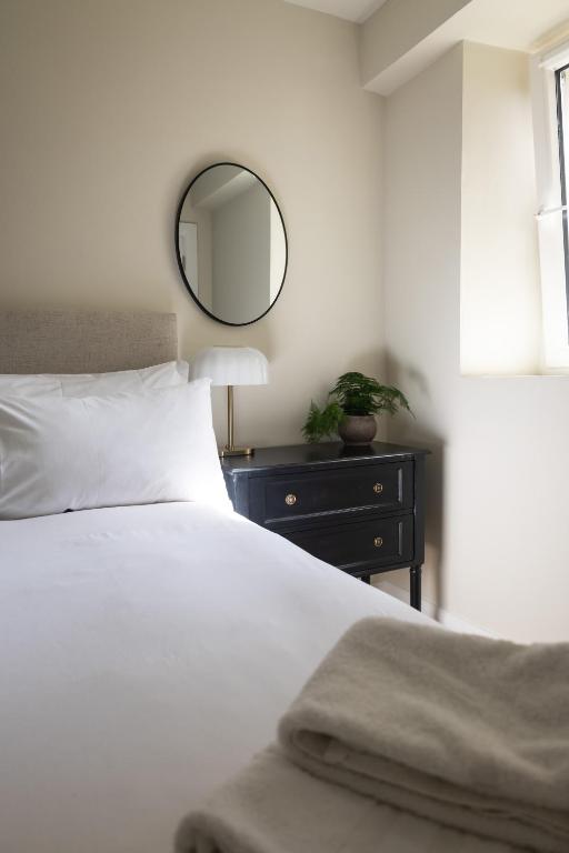 a bedroom with a white bed and a mirror at The Yard Dungarvan in Dungarvan