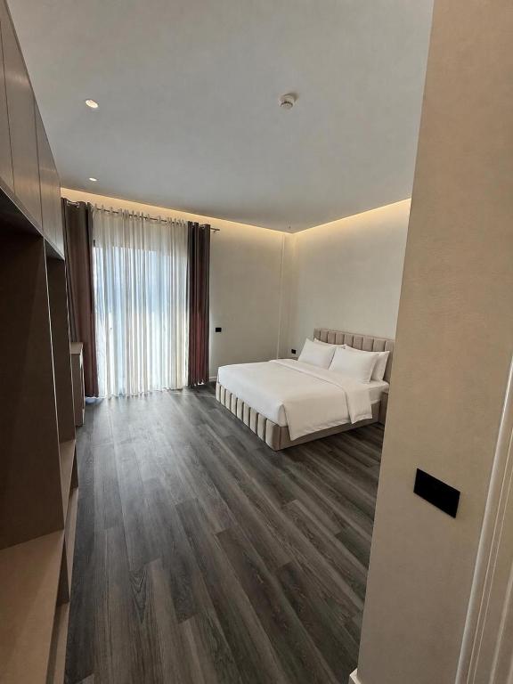 a bedroom with a white bed and a large window at Merlis Hotel in Kusarth