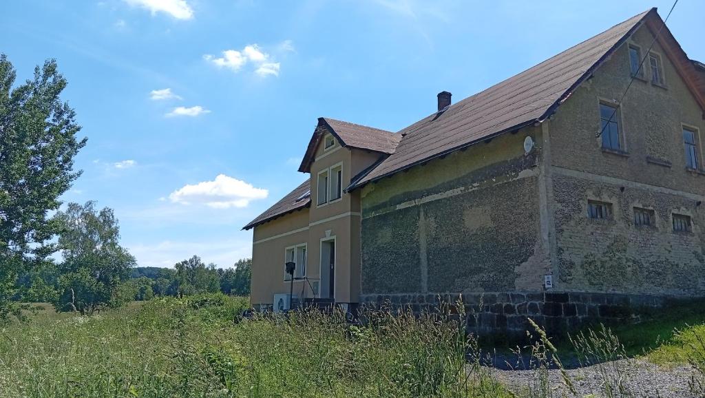an old brick house on a grassy field at Zimmerův Statek in Mikulášovice