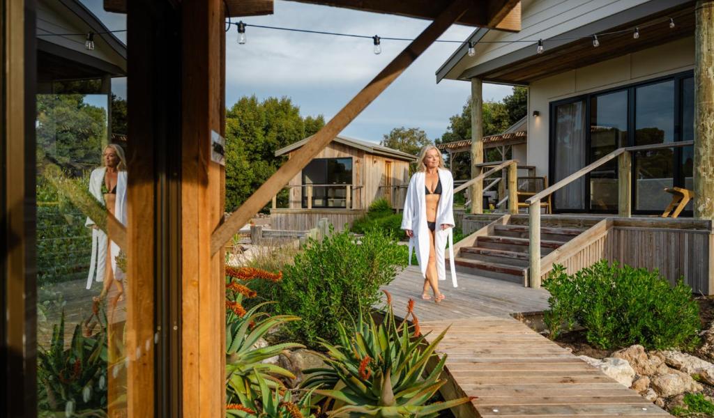 two women walking on a wooden walkway outside a house at The Sanctuary at Bayside Glamping in Marion Bay