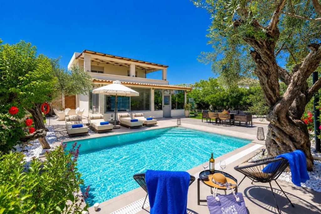 a swimming pool with chairs and a house at Villa Ammos in Afantou