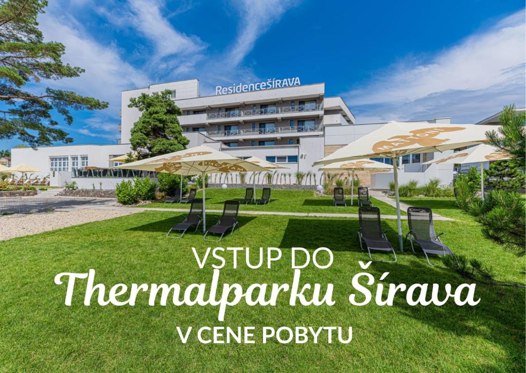 a building with chairs and umbrellas in a park at Residence Šírava *** in Kaluža