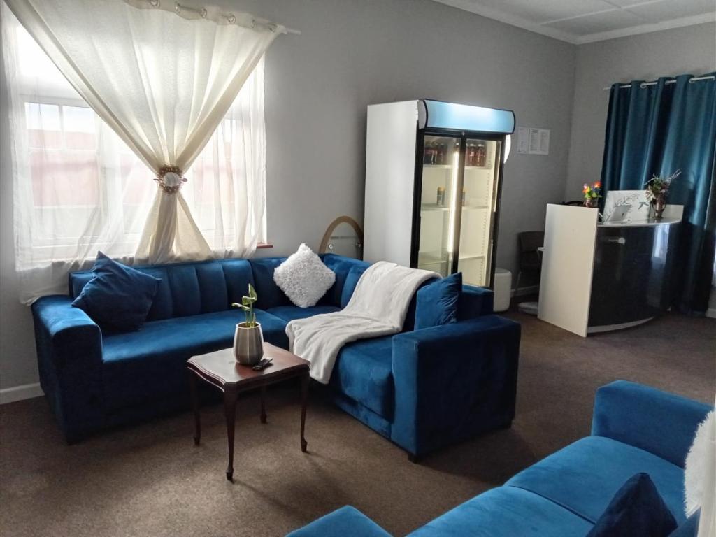 a living room with blue couches and a table at Great Choice BnB in Goodwood