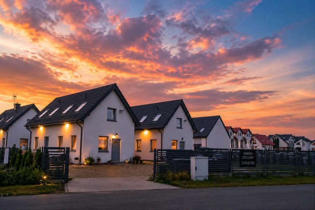 a row of houses with a sunset in the background at Domki Osada Kalinowa Nowęcin Łeba Sauna in Łeba