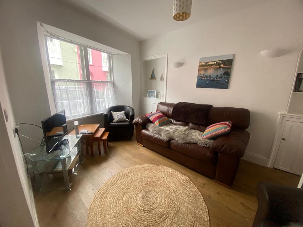 a living room with a brown couch and a table at Central Spacious 3 Bed Cottage, Sleeps 5 in Tenby