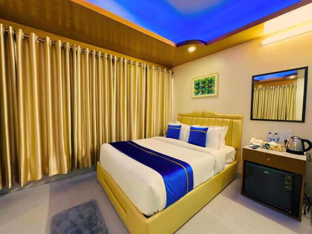 a bedroom with a large bed with blue pillows at The Ambassador Hotel Dhaka in Dhaka