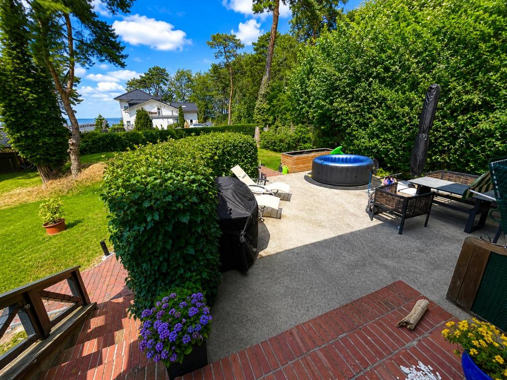 a garden with a bench and a large hedge at Ferienhaus Hugo in Lubmin