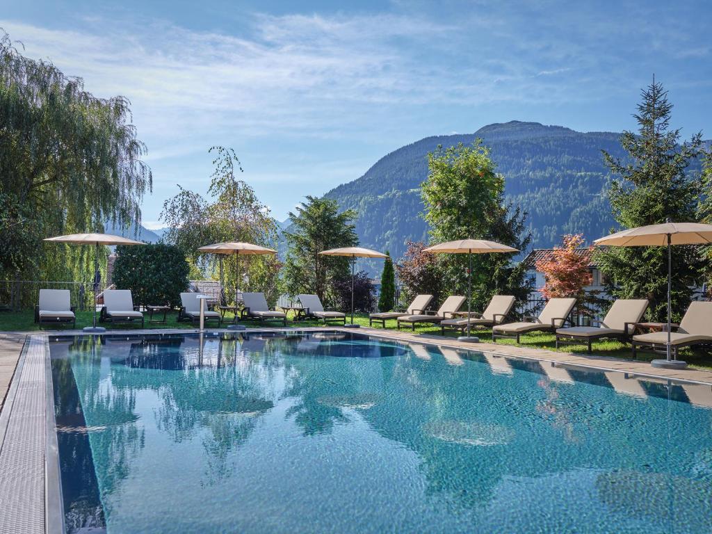 a swimming pool with chairs and umbrellas at Löwen Hotel Montafon in Schruns