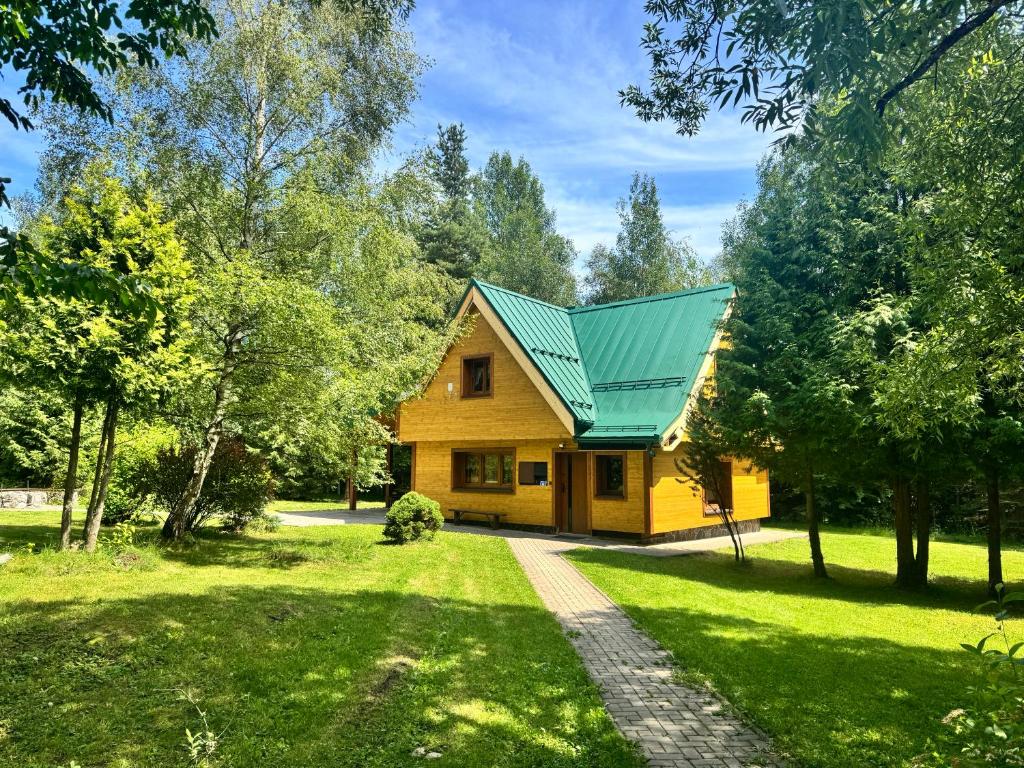 a yellow house with a green roof at Chata ALPINA 1 in Tatranská Lomnica