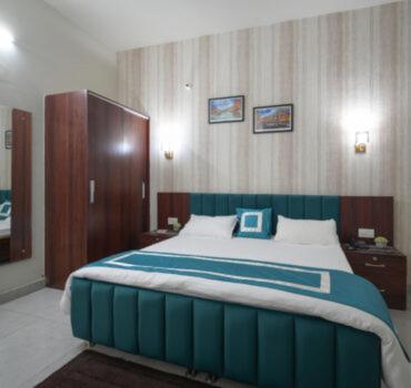 a bedroom with a large bed with a blue headboard at Hotel Riddhinn6 in Jalandhar