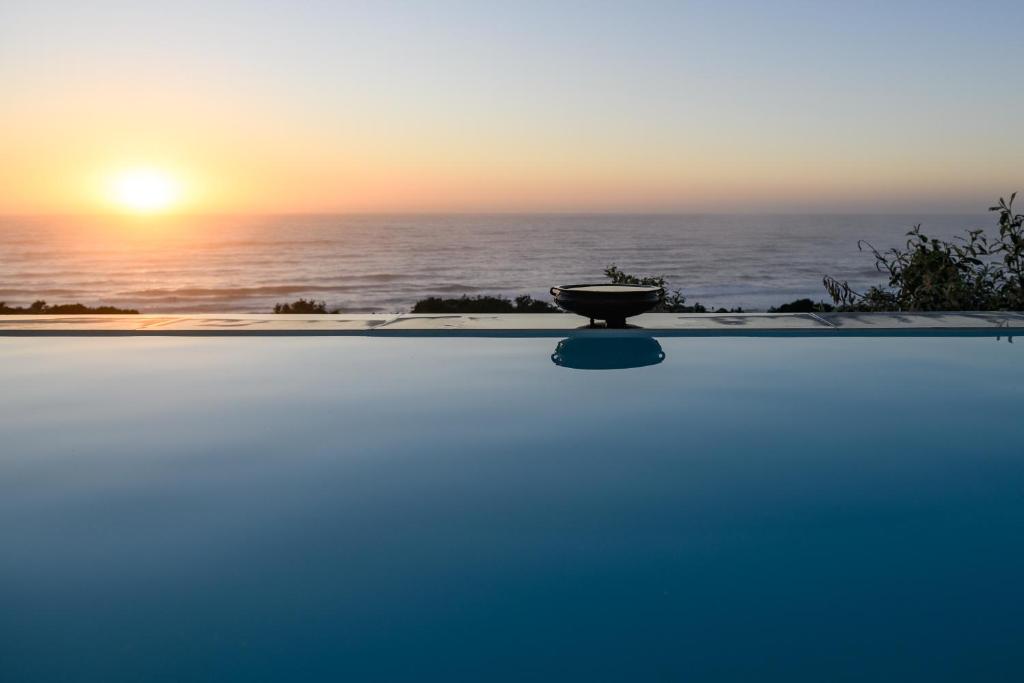 a pool with the sunset in the background at Nakai Beach Homestay in Trafalgar