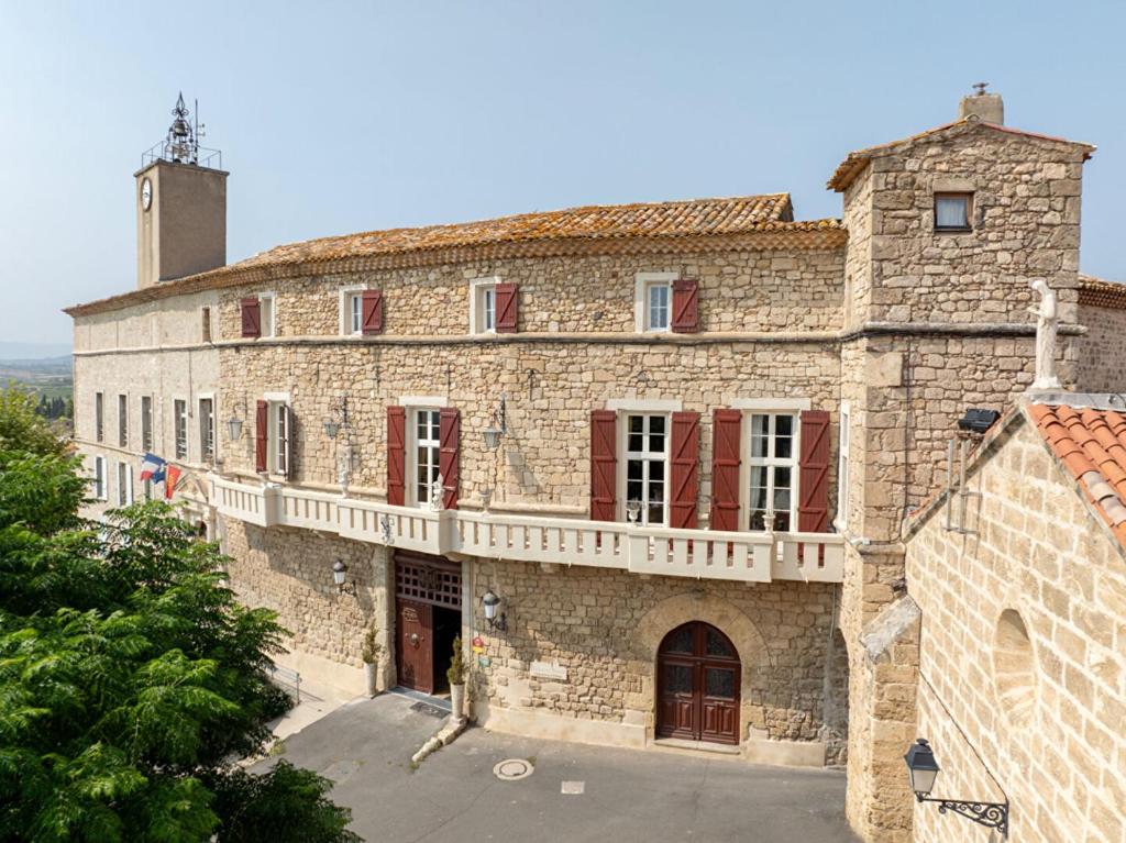 a large stone building with red windows and a tower at Chateau de Murviel in Murviel