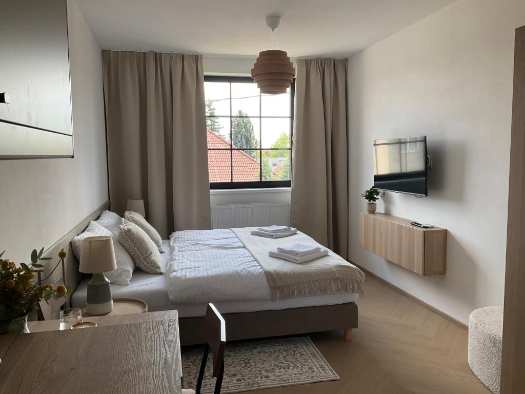 a white bedroom with a bed and a window at Ivanka Apartments in Ivanka pri Dunaji