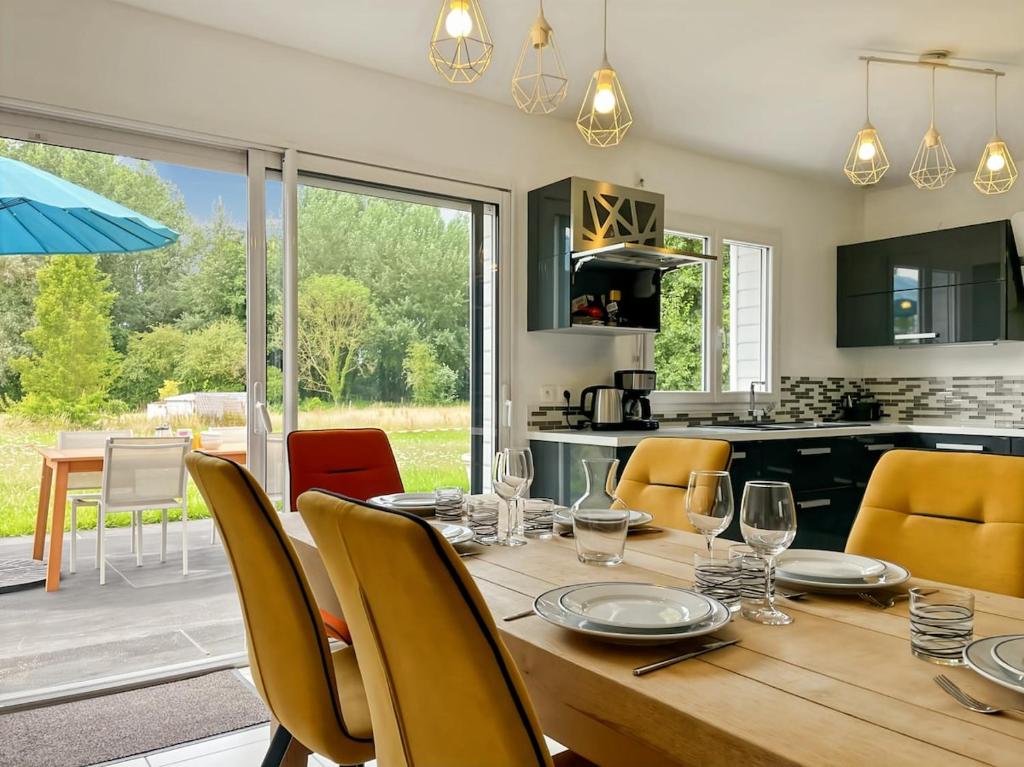 a kitchen and dining room with a wooden table and chairs at L'Abri Côtier, maison spacieuse avec jardin in Pendé