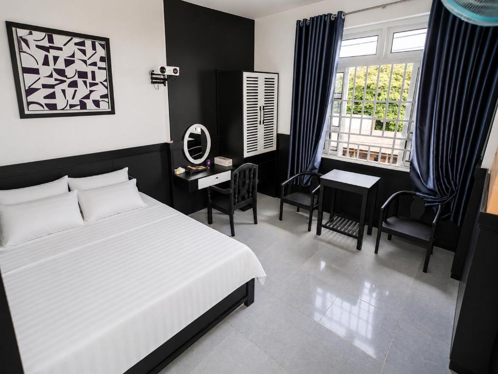 a bedroom with a bed and a table and chairs at The Luxe Homestay in Buôn Ðũng