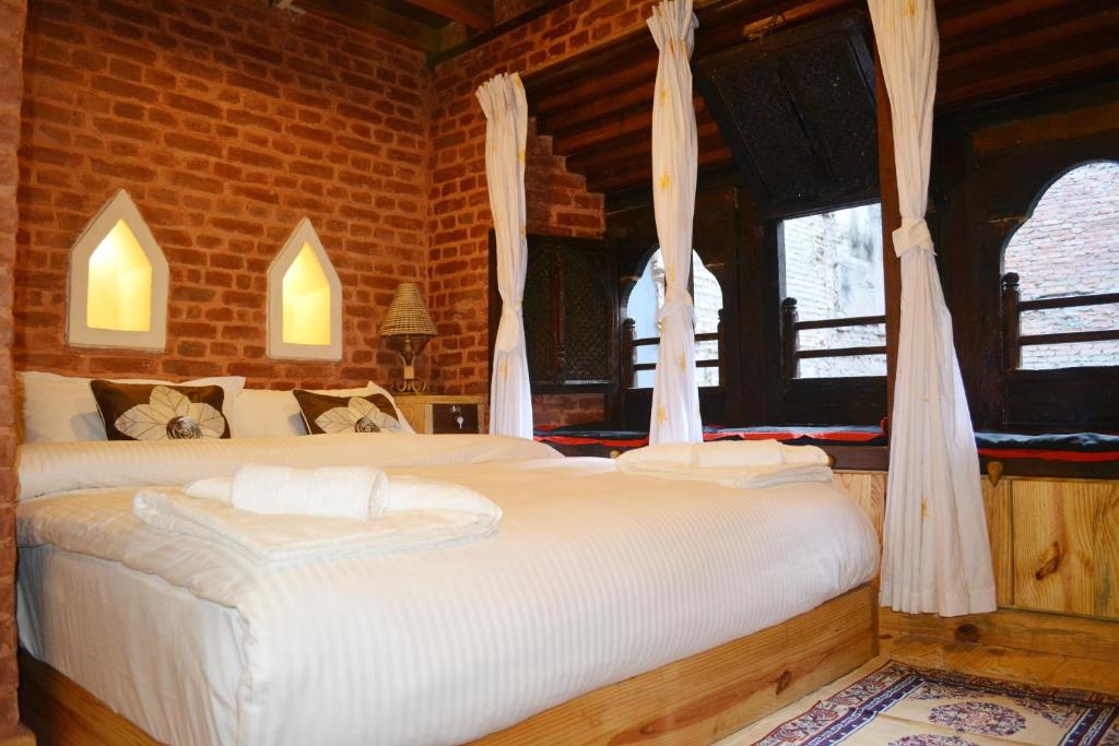 a bedroom with two beds and two windows at Yamba Traditional Home in Pātan