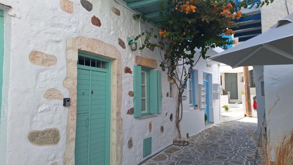 a building with green doors and a tree on a street at Cavo Paradise Studio Cyclades in Kimolos