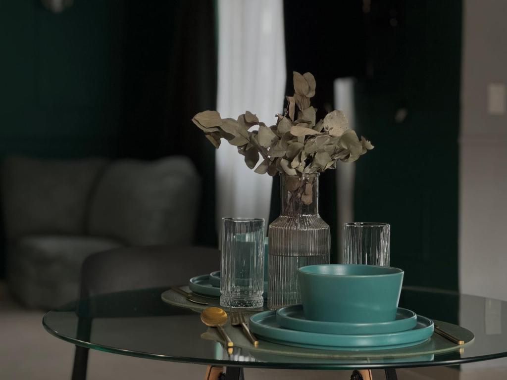 a glass table with a vase of flowers and glasses at Tandem - Espacio para dos - Cama King - Parking in Maipú