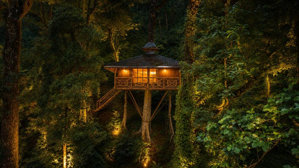 a tree house in the forest at night at Soma Seven Springs Resort in Munnar