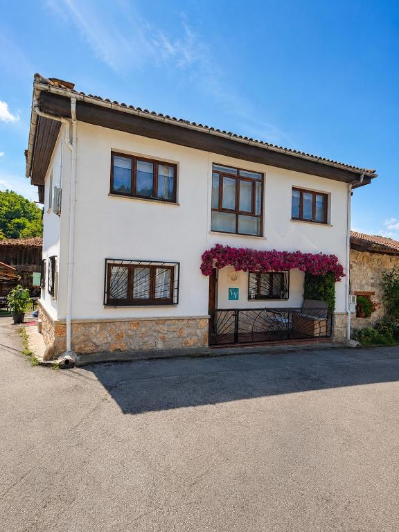 a large white house with flowers on it at La Olivia 53 Boutique con zona Chill Out A 5 min de Cangas de Onís in Cangas de Onís