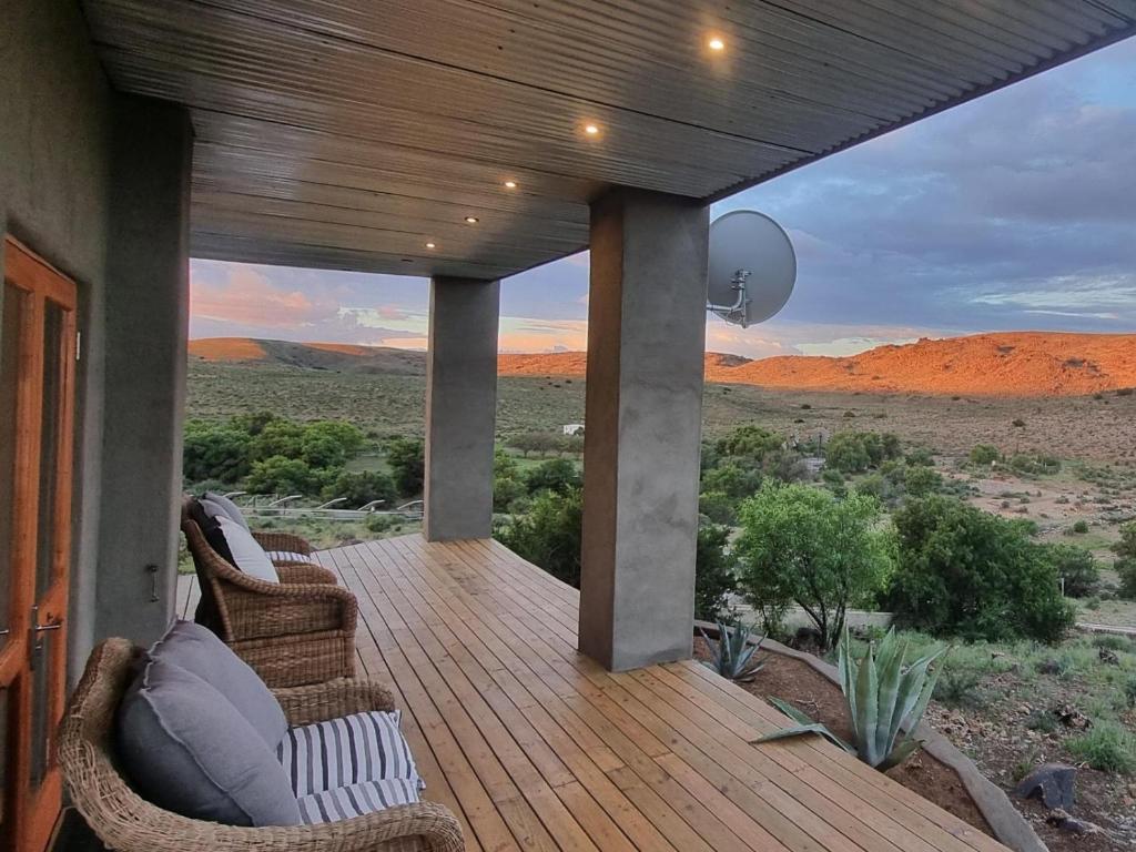 a porch with wicker chairs and a view of the desert at Oudam Cottage in Carnarvon