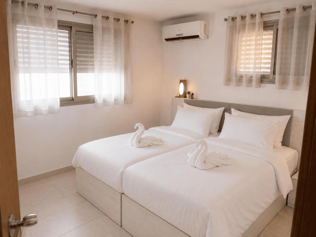 two beds in a bedroom with swans on them at נוף יבנאל in Yavneʼel
