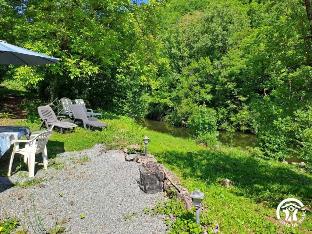 a group of benches sitting in the grass near a river at Moulin de Record in Ferrières