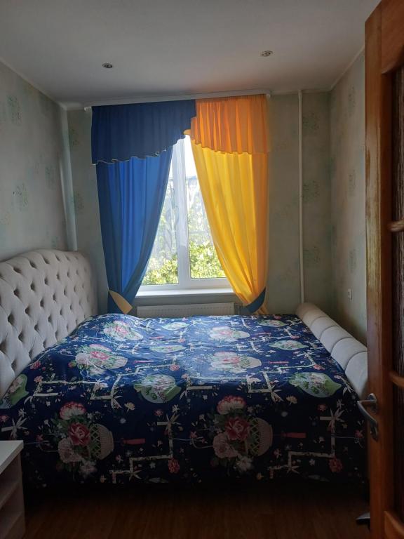 a bedroom with a bed with a colorful comforter and a window at MERE Apartment in Sillamäe