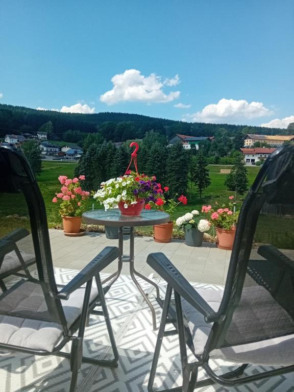 a table and two chairs on a patio with flowers at Ferienwohnung in Arrach