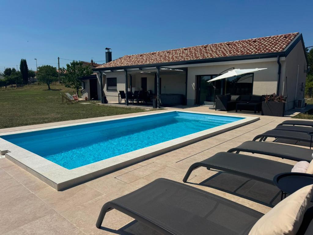 a swimming pool with chairs and a house at Capo House in Gračišče