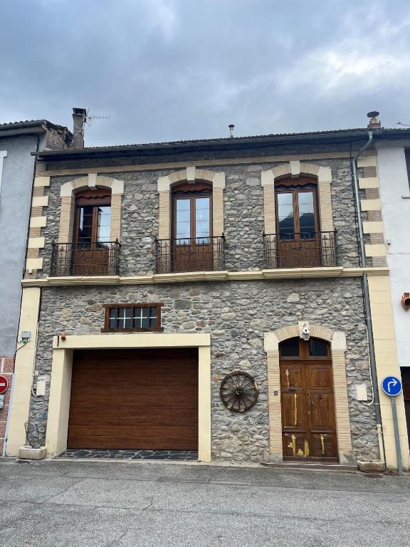 a stone building with two garages and two garage doors at Sporting Pyrenées House in Vicdessos