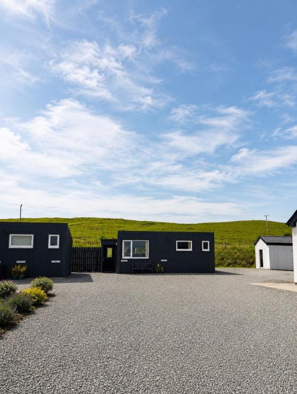 a black tiny house sitting on top of a gravel lot at Minch View Cabin 2, 1 Earlish in Earlish