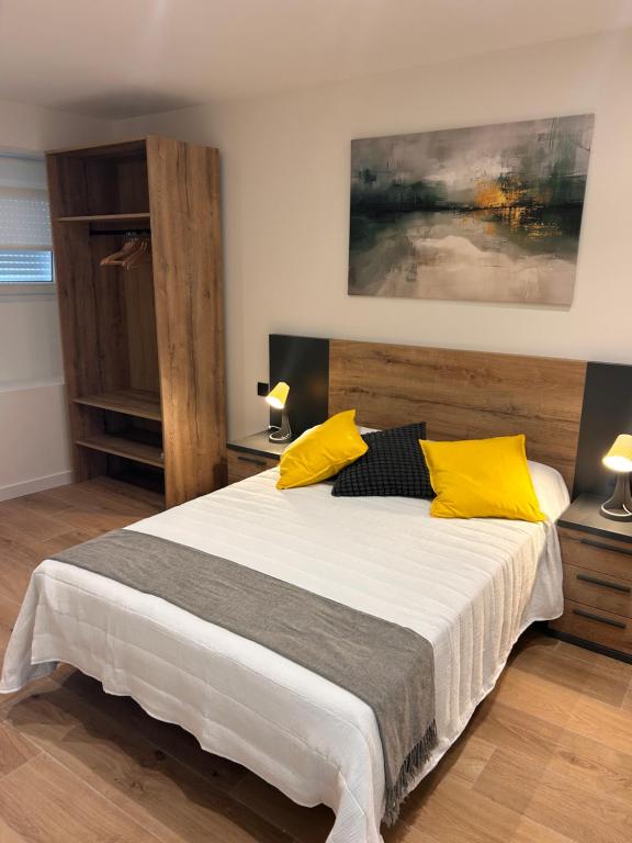 a bedroom with a large bed with yellow pillows at MTM Rooms in Santander